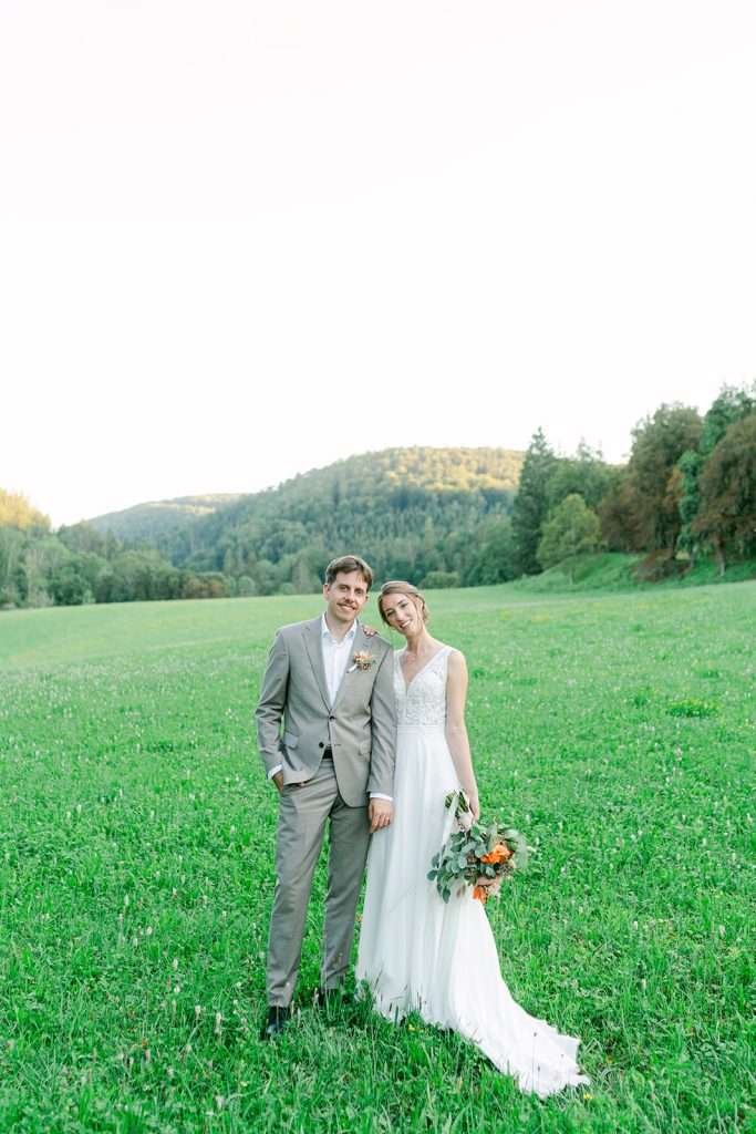 A bride and groom walk through a field in the countryside of Switzerland during their elopement.
