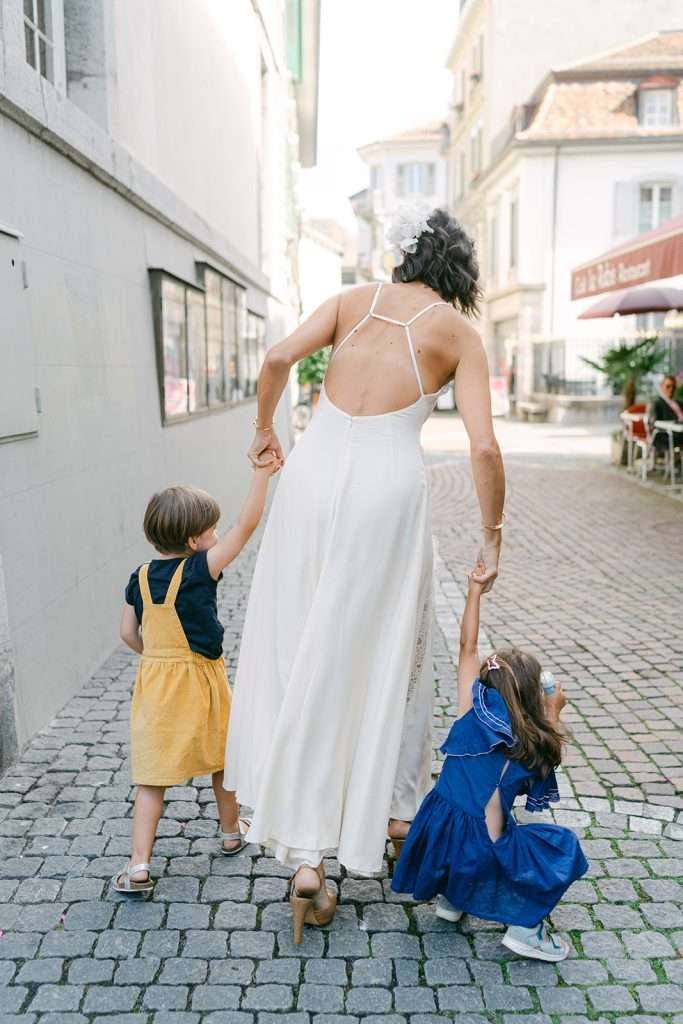 A bride walking hand in hand with her children.