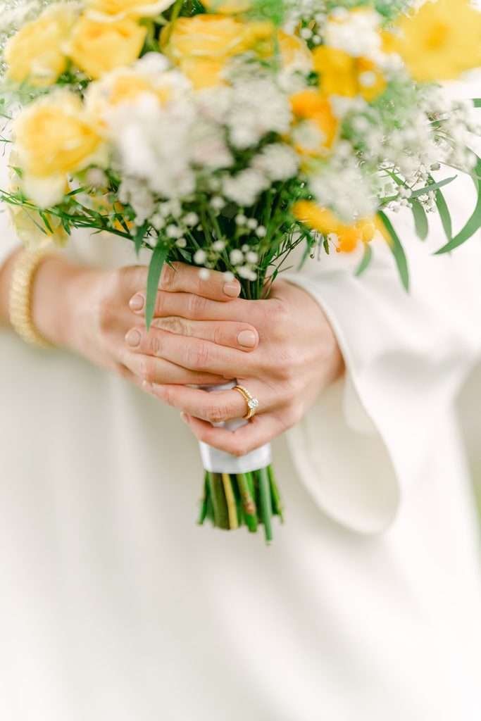 A bride holding her bouquet and showing her ring.