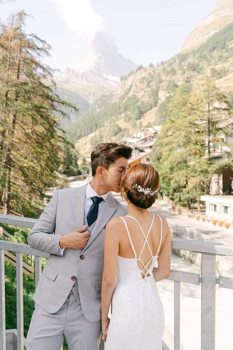 A couple kissing each other in front of the Matterhorn.