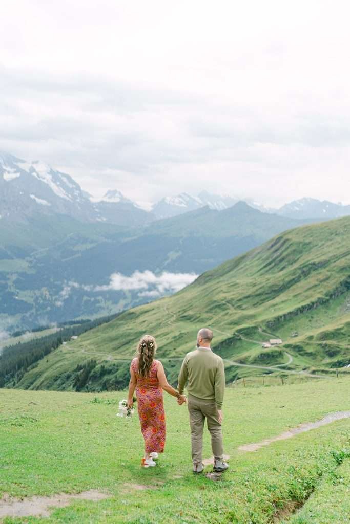 A couple walking hand in hand in Grindelwald, during their engagement photo session.