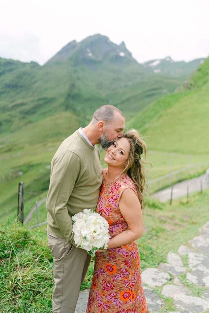 A man kissing his fiancée in Grindelwald, during their photo session.
