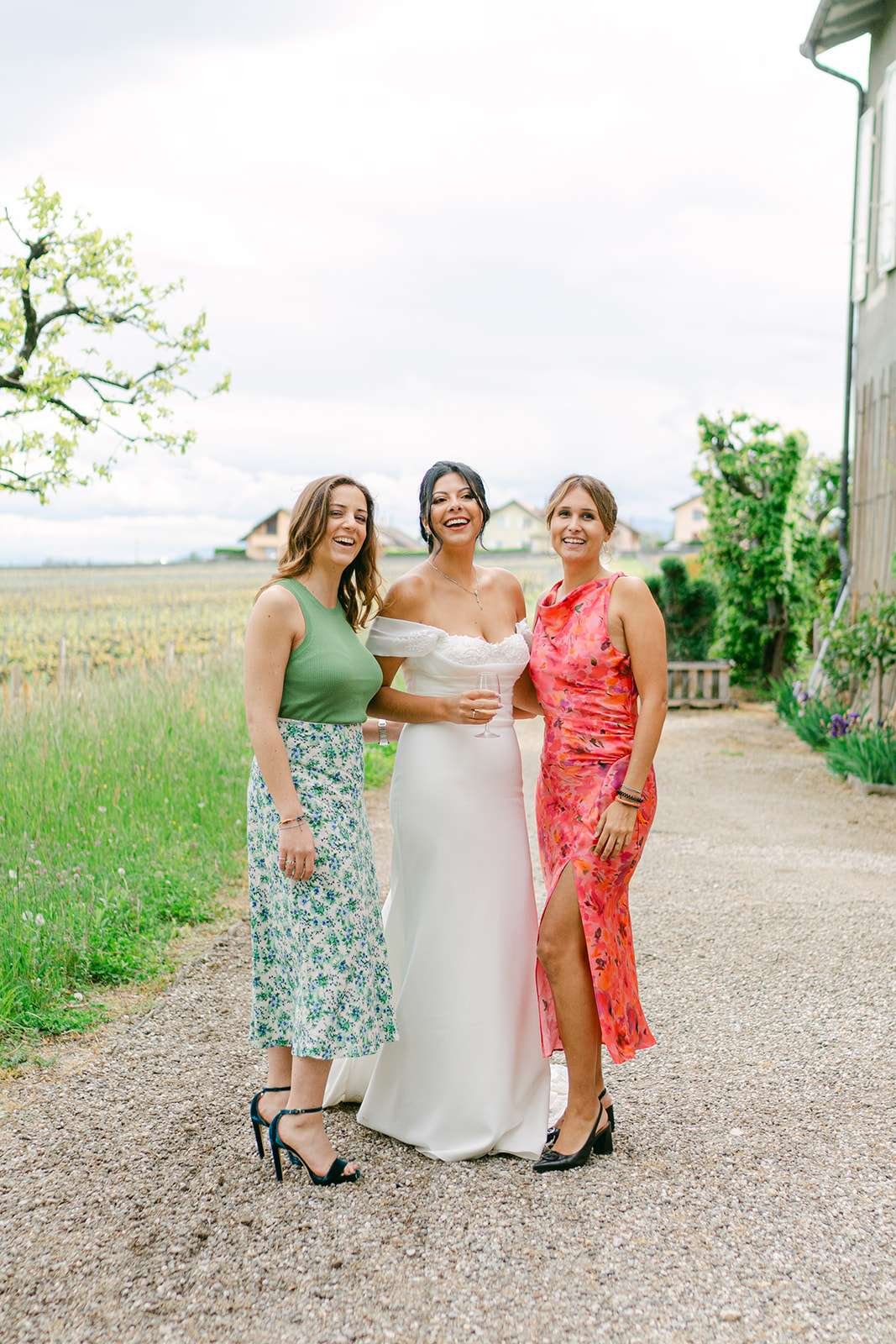 A bride laughs while standing with friends in the gardens