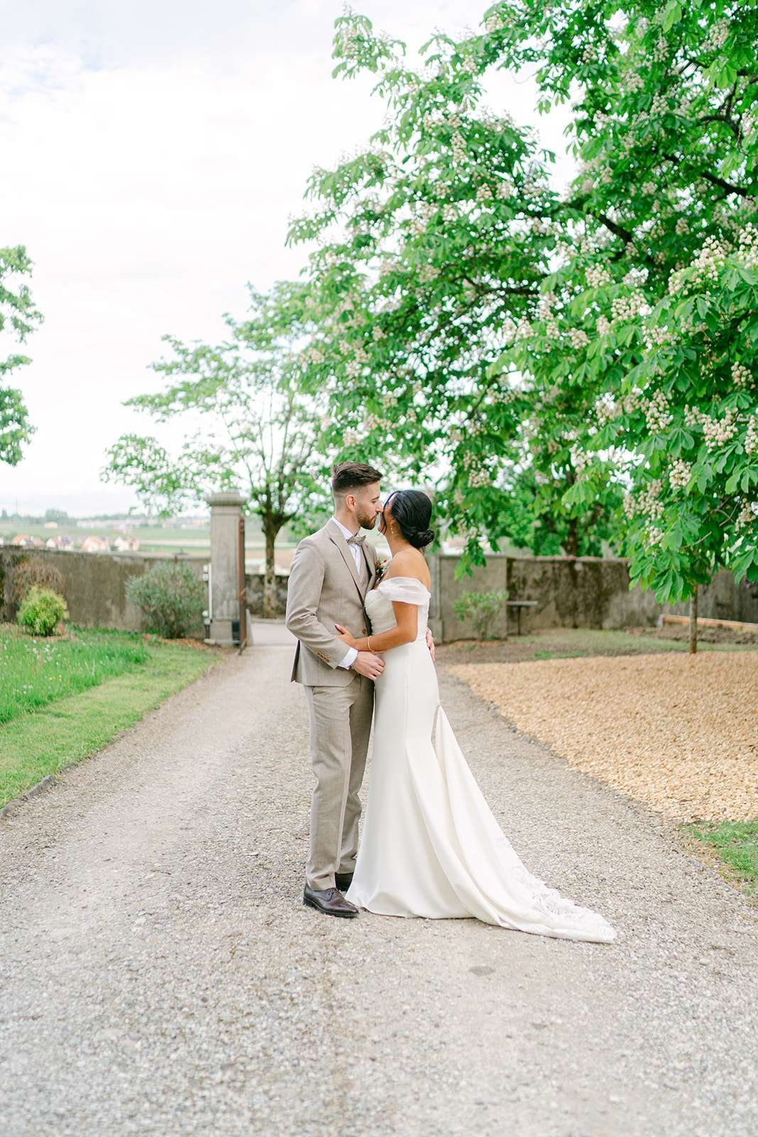 Newlyweds snuggle in the gravel driveway of Château de Luins
