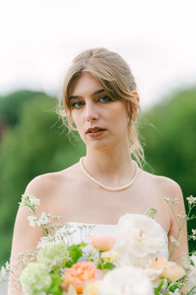 A bride walks in a garden holding her white and pink bouquet