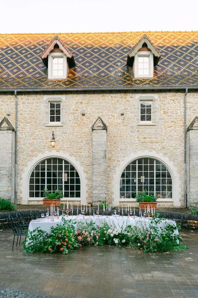 Details of a curved reception table set up in the gardens with candles for a Domaine de Bournel wedding