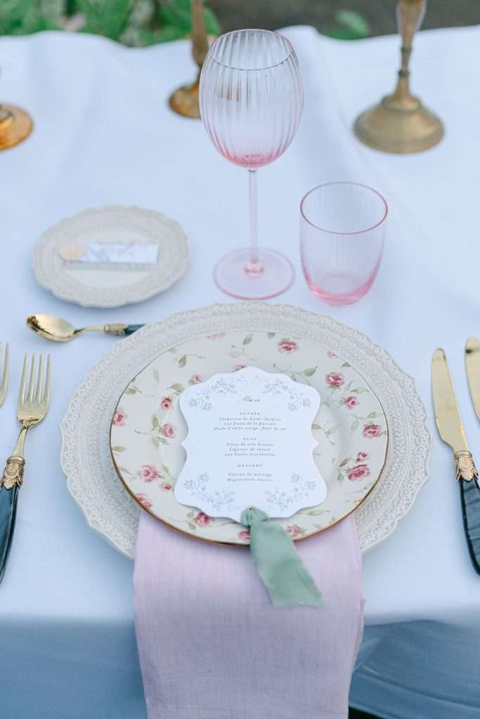 Details of a place setting with menu, pink napkin and gold utensils