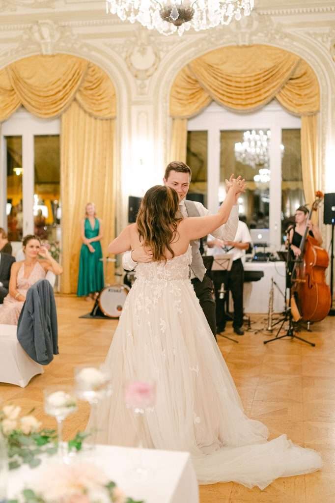 A bride and groom dance for the first time to a live band under chandeliers