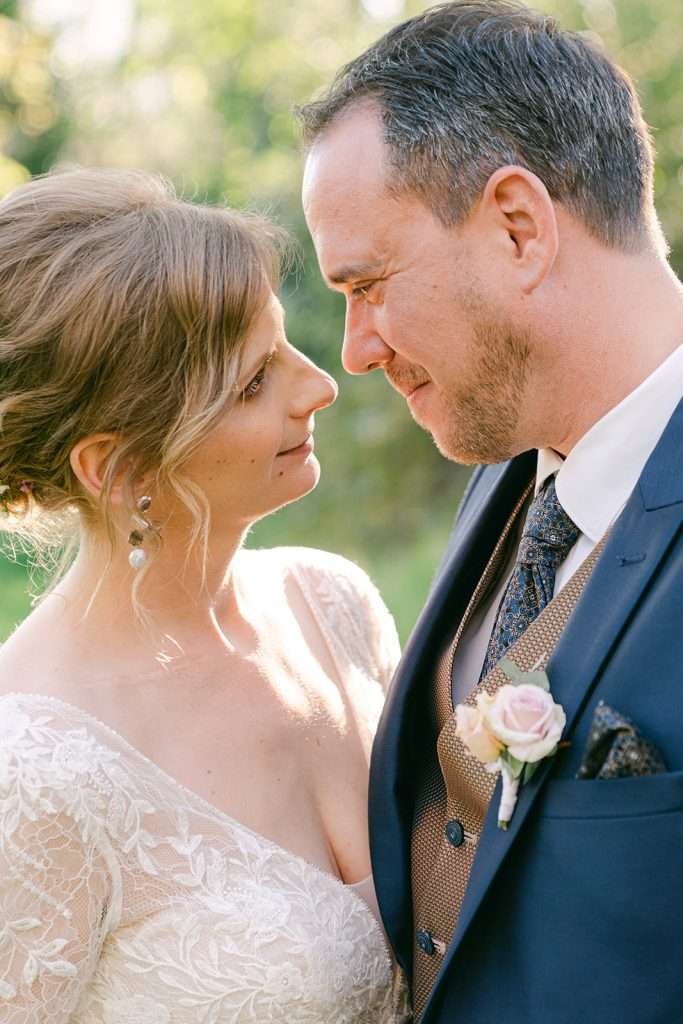 Newlyweds stare into each other's eyes while standing in a garden at sunset