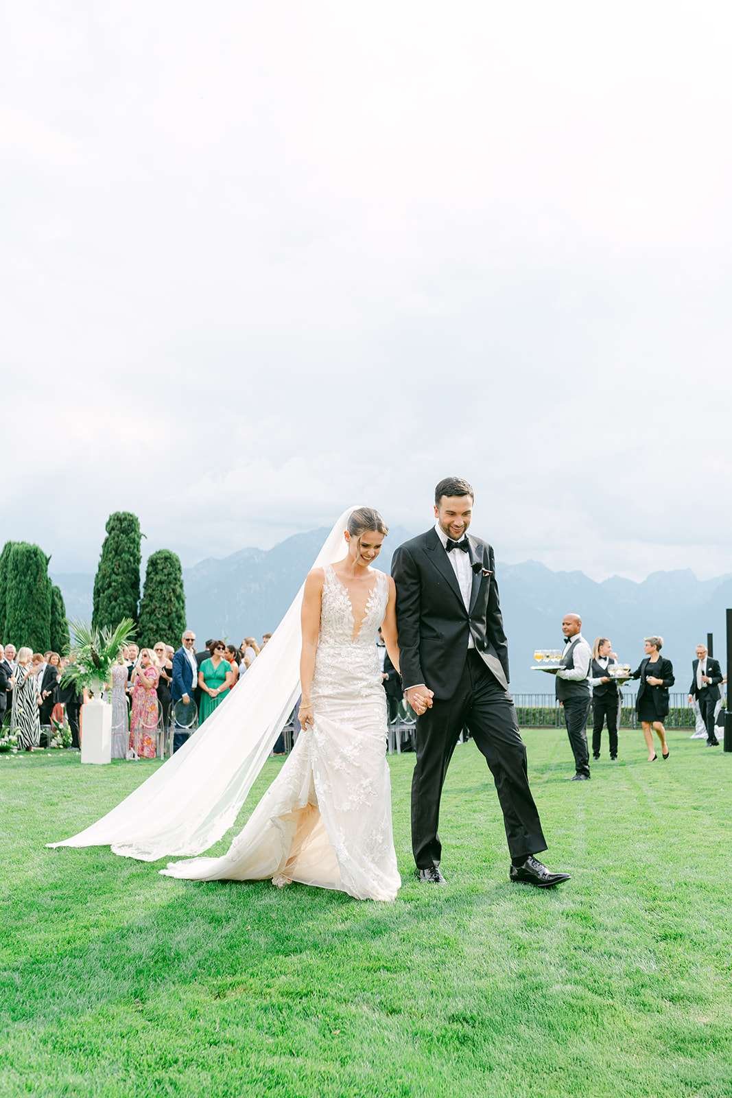 Newlyweds walk the lawn holding hands exiting their ceremony at their destination wedding in Switzerland