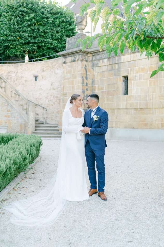 Happy newlyweds hold hands while exploring the gardens of Hotel du Peyrou