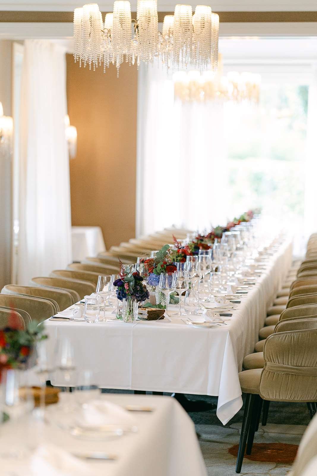 A look down a long wedding reception table set up with white linen and floral centerpieces at Villa Schweizerhof Lucerne