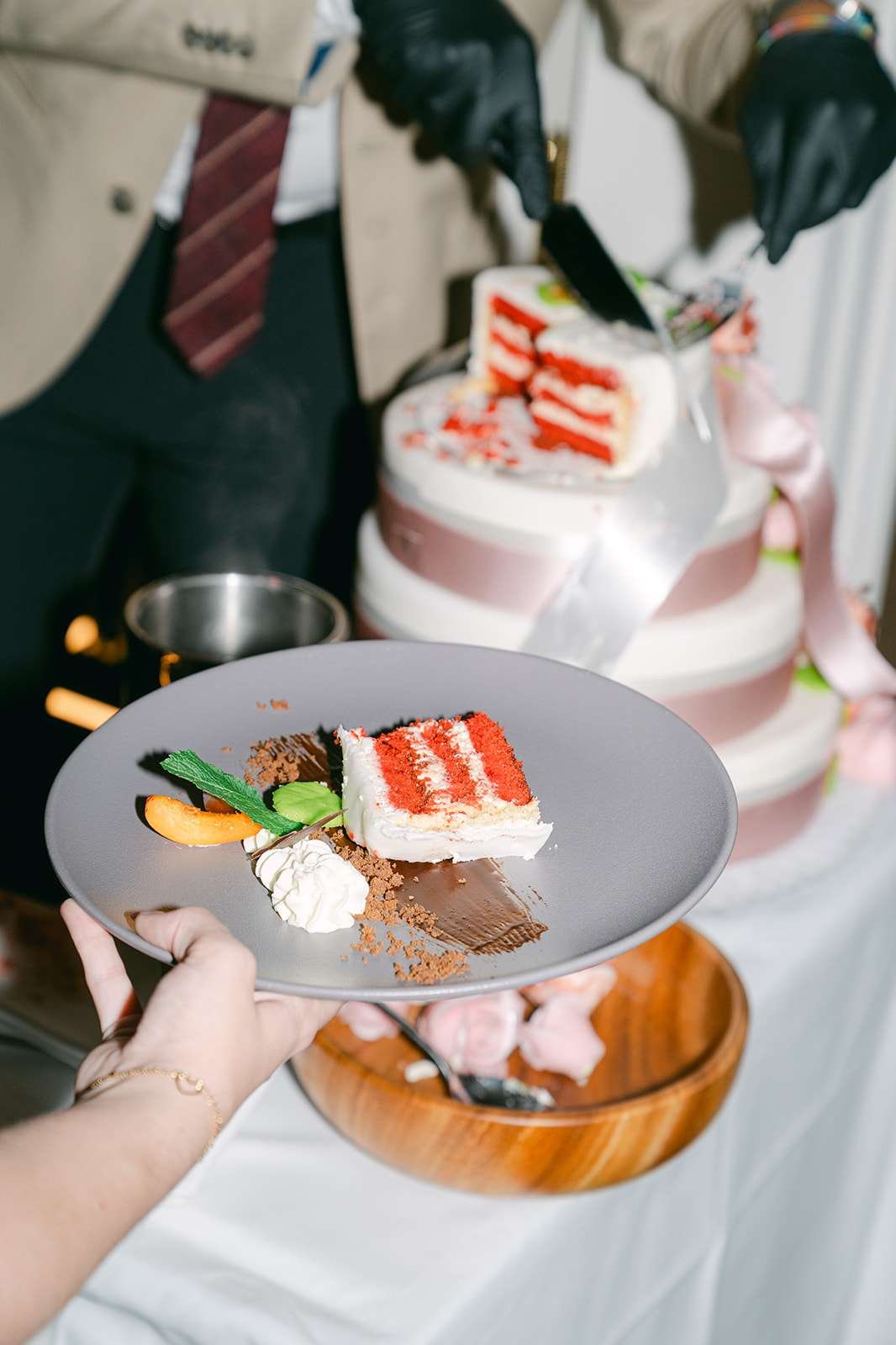 Details of a slice of wedding cake prepared on a plate with fruit and other accents